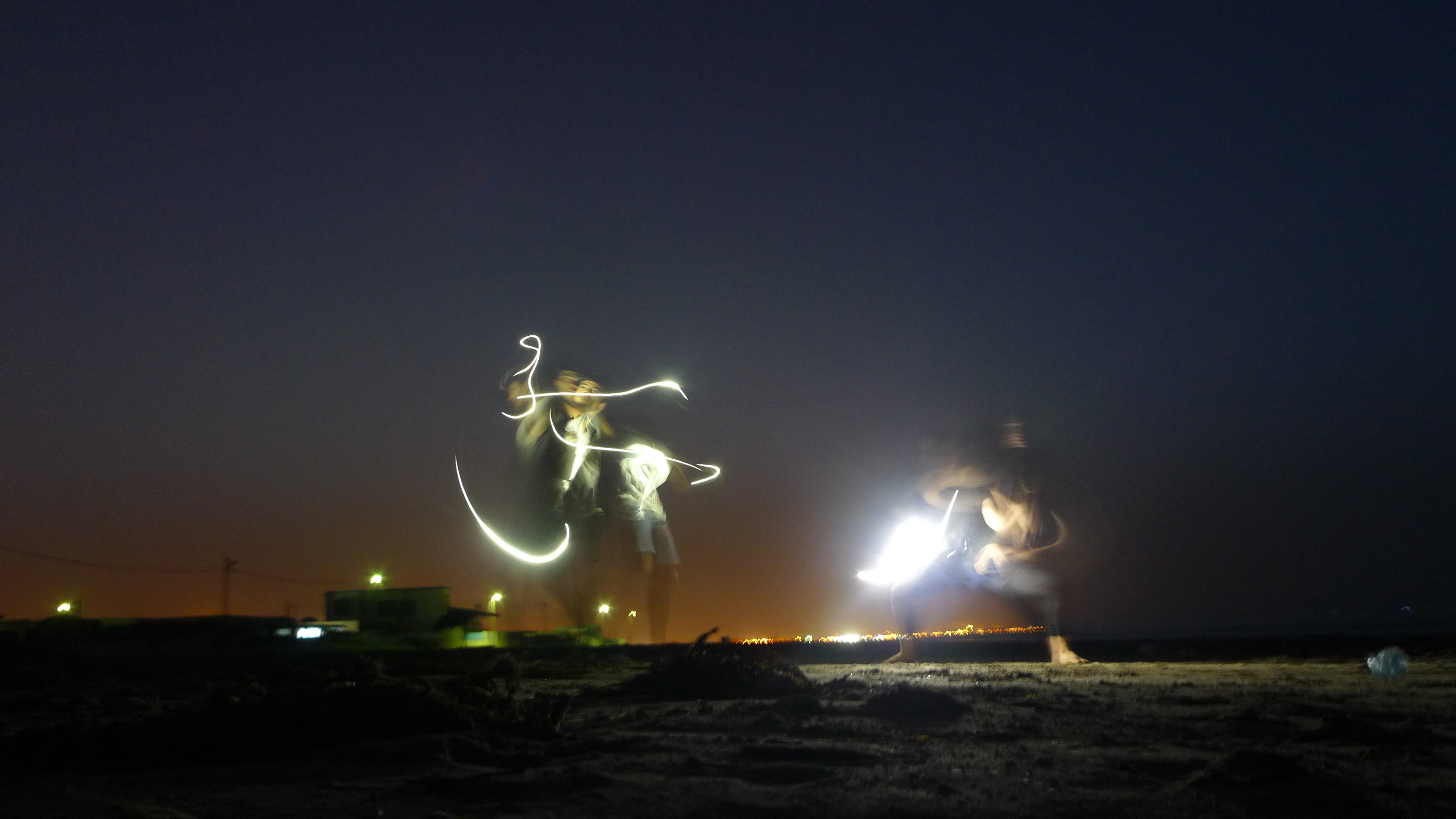 Sur la plage une performance s’improvise dans la nuit, éclairée par la lumière des téléphones portables